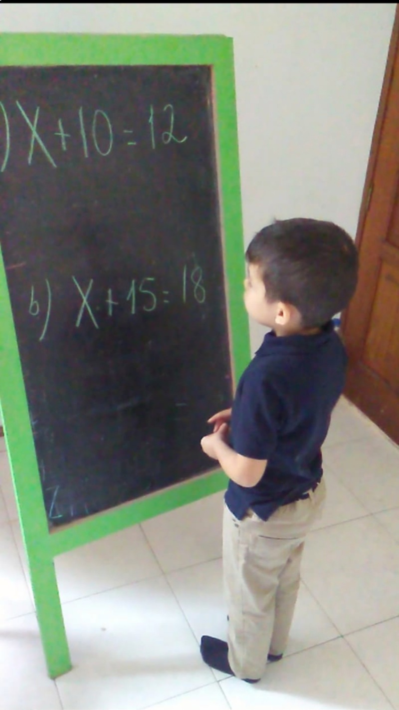 Niño con 4 años de edad en clase presencial resolviendo ecuaciones de 1er grado.