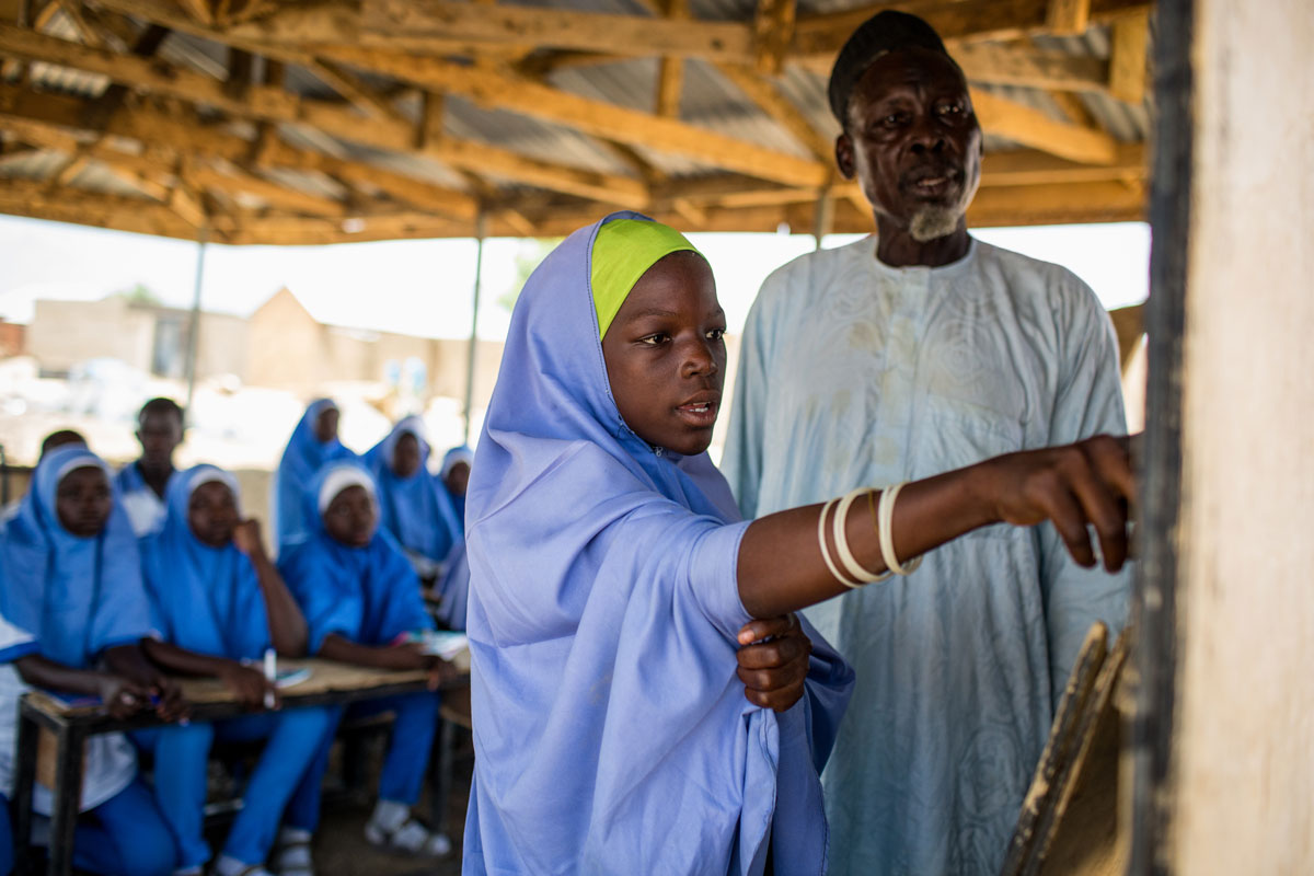 Nigeria: después de una ocupación militante de su aldea, Hawa, de 12 años, aprende bajo la guía de su maestro, Al Haji El Saddiq (derecha). Ella tiene un poderoso sentido del propósito. “Si aprendo, los más jóvenes de la comunidad aprenderán como yo”. Crédito: UNICEF